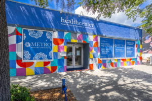 A photo of the exterior of our METRO location on Central Avenue in St. Pete. Sunny day with a bright blue, multi-colored mural on building exterior.