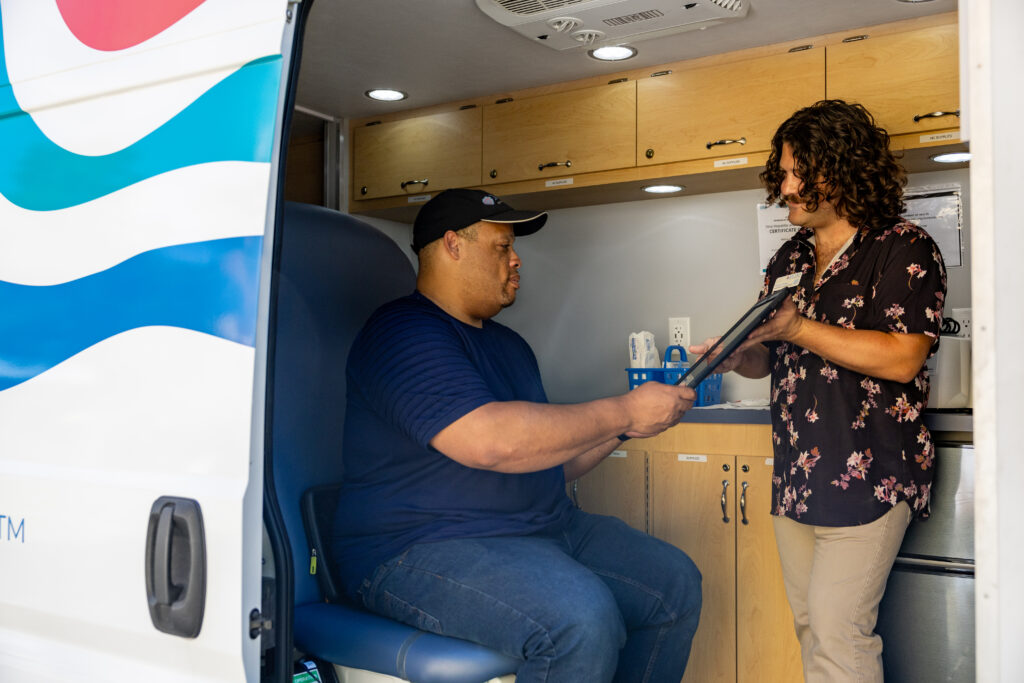 A Prevention & Sexual Health Specialist having a customer sign off on e-waivers in METRO's Mobile Testing Van.