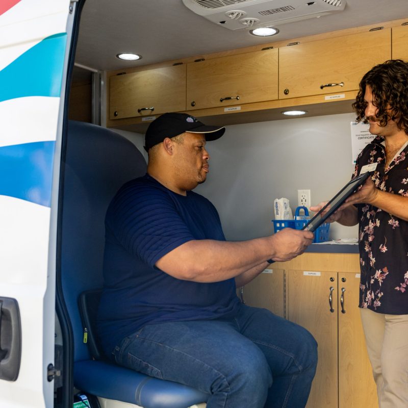 A Prevention & Sexual Health Specialist having a customer sign off on e-waivers in METRO's Mobile Testing Van.